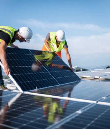 Team of two engineers installing solar panels on roof.